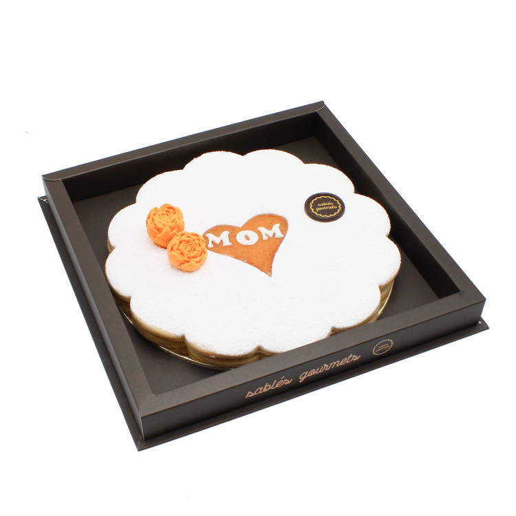 Heartfelt apricot Tart for Mom – A handcrafted almond tart dusted with powdered sugar, featuring a heart-shaped “MOM” design, an ideal treat for Mother’s Day.