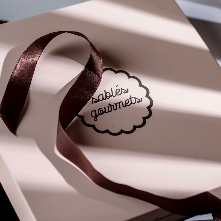 An elegant lifestyle shot of a medium gift box with buttery Sablés and premium chocolate treats