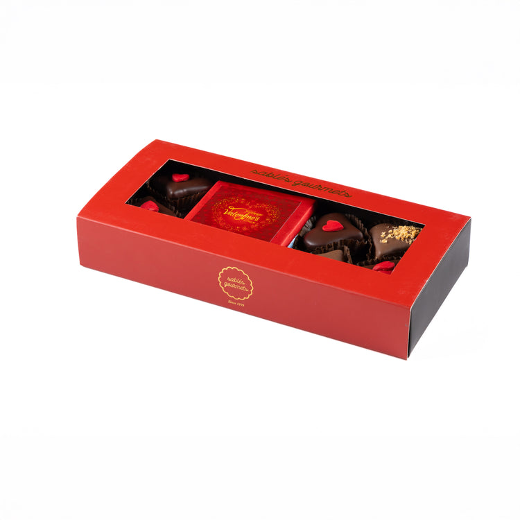Red chocolate box with a clear lid displaying various chocolates on a white background
