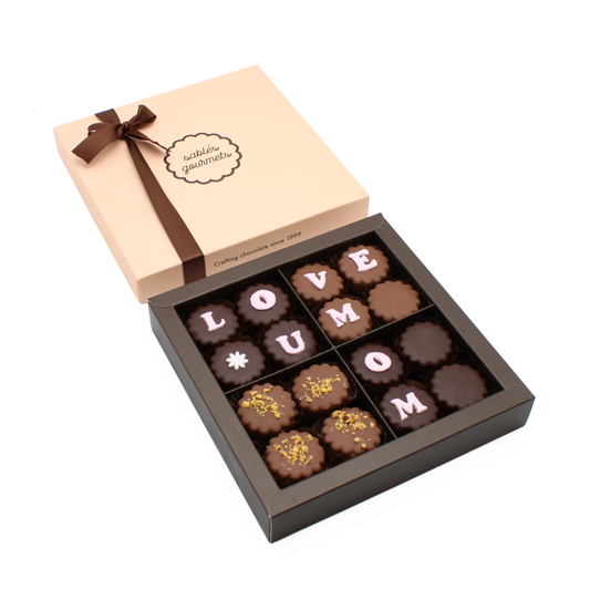 Mom’s Sweet Indulgence Tray – A gourmet chocolate arrangement with pralines, chocolate-coated sablés, and delicate decorations, perfect for Mother’s Day.