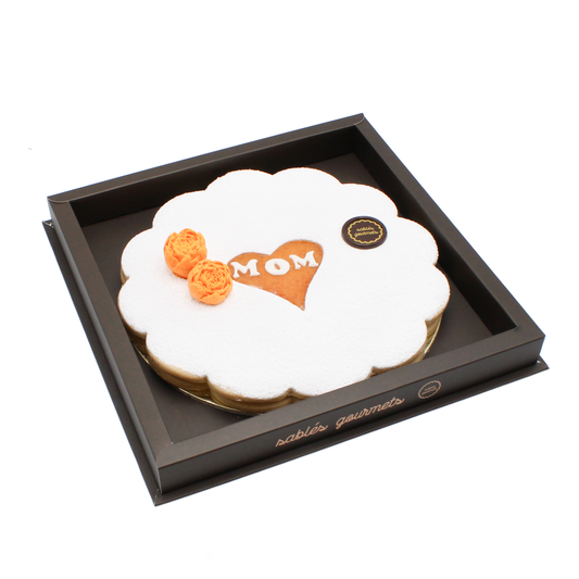 Heartfelt apricot Tart for Mom – A handcrafted almond tart dusted with powdered sugar, featuring a heart-shaped “MOM” design, an ideal treat for Mother’s Day.