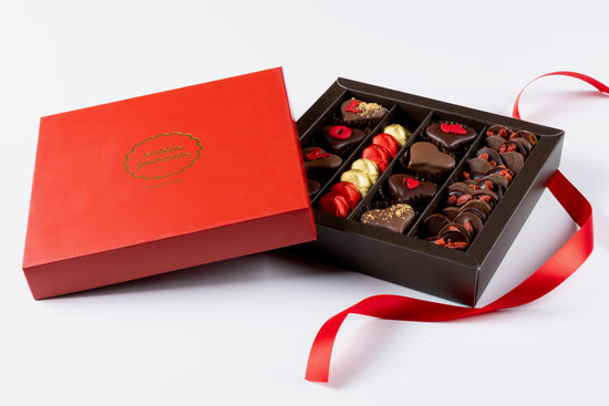 Open chocolate box with a red ribbon on a white background