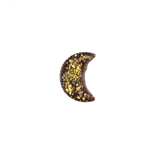 Chocolate crescent moon with pistachio pieces on a white background