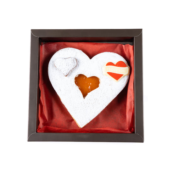 Heart-shaped cookie with a filling in a decorative box on a white background